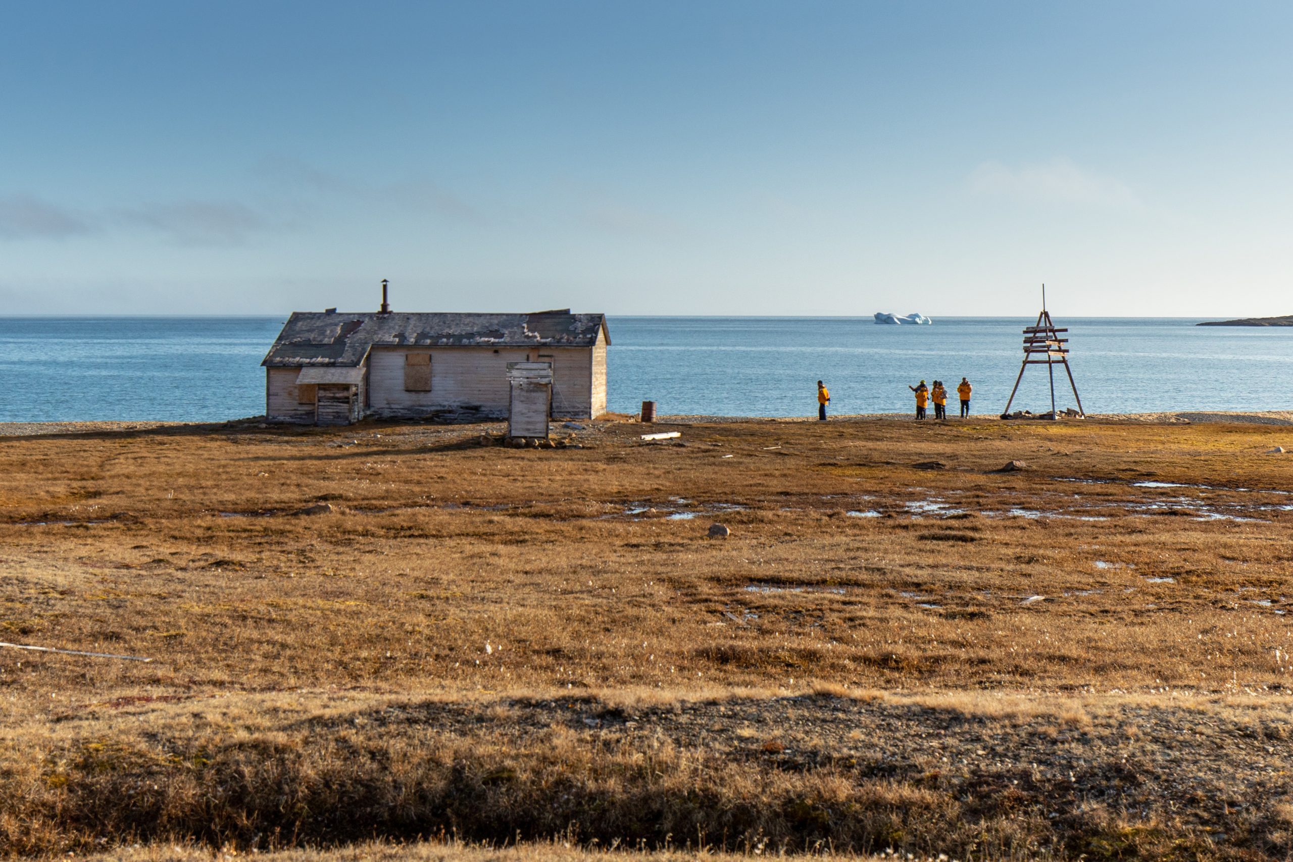 Guests standing on shore next to historic hut in the Northwest Passage.