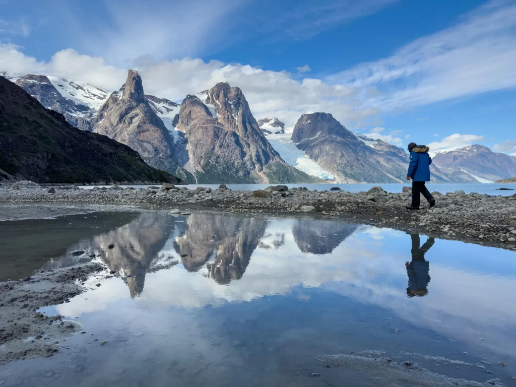 Guest hiking near pond & mountains in Greenland. 