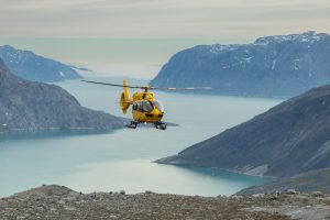 A helicopter flying above large fjord. 