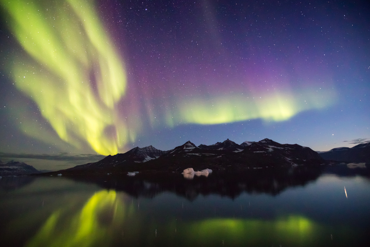 Spectacular northern lights shining above mountains in East Greenland.