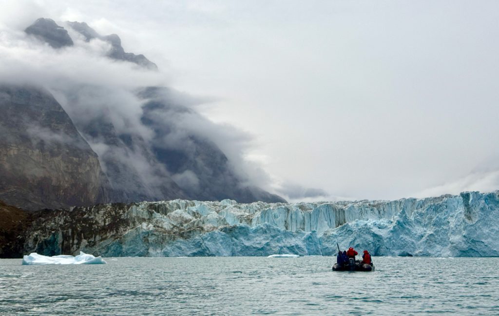 A zodiac full of guests exploring a glacier face. 