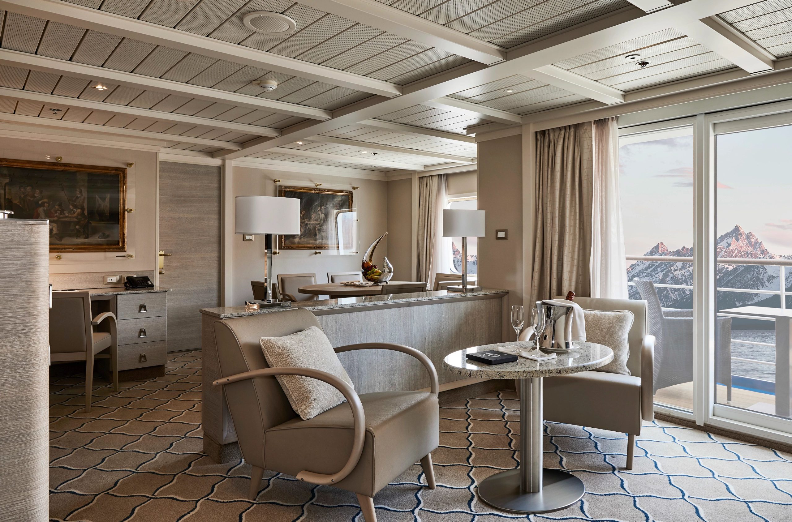 Owner's Suite on Silver Cloud with two chairs, small table, circular dining table, desk and private balcony