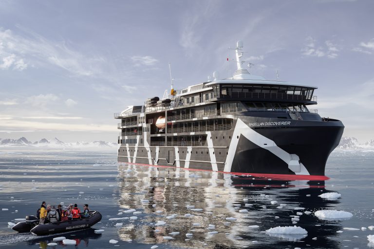 A zodiac with guests cruising in icy waters towards the Magellan Discoverer ship.