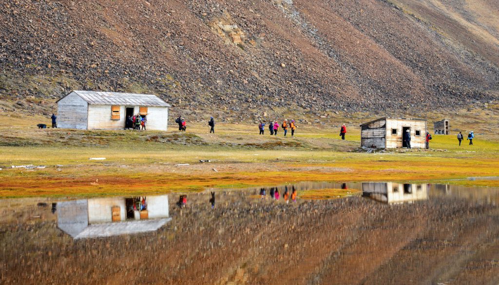 Guests walking on shore near huts.