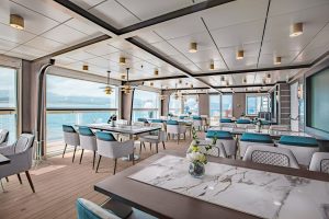 The specialty restaurant on Ocean Victory with various tables ang huge ocean view windows.