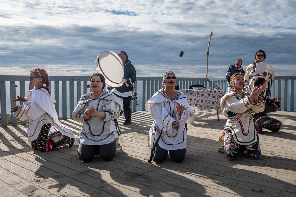 Inuit guests performing in traditional dress on the deck of ship. 