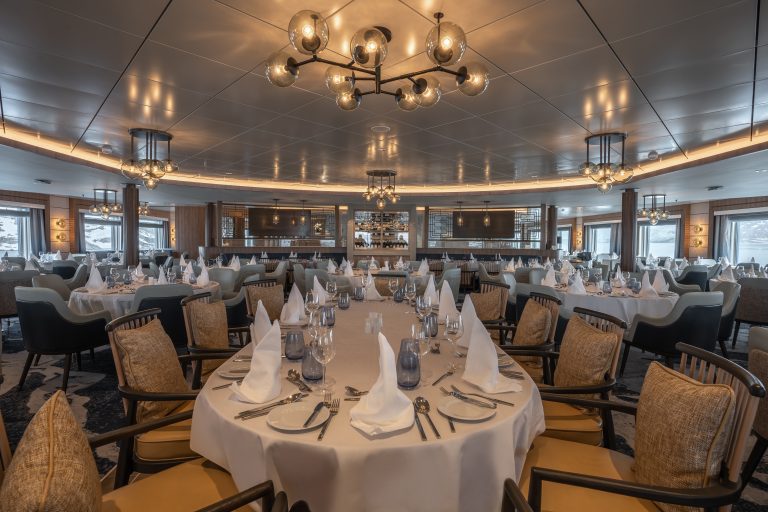 Main restuarant on the Ocean Albatros with white tablecloths and large windows.