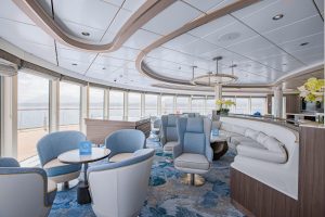 Ocean Victory observation lounge with chairs & sofas and floor to ceiling windows.