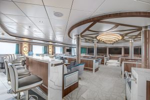 The lecture room on Ocean Victory showing multiple rows of seating, large flat screen TV's and windows.