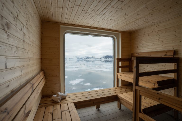 View from inside the sauna with wooden benches and huge picture window looking out onto the polar landscape.