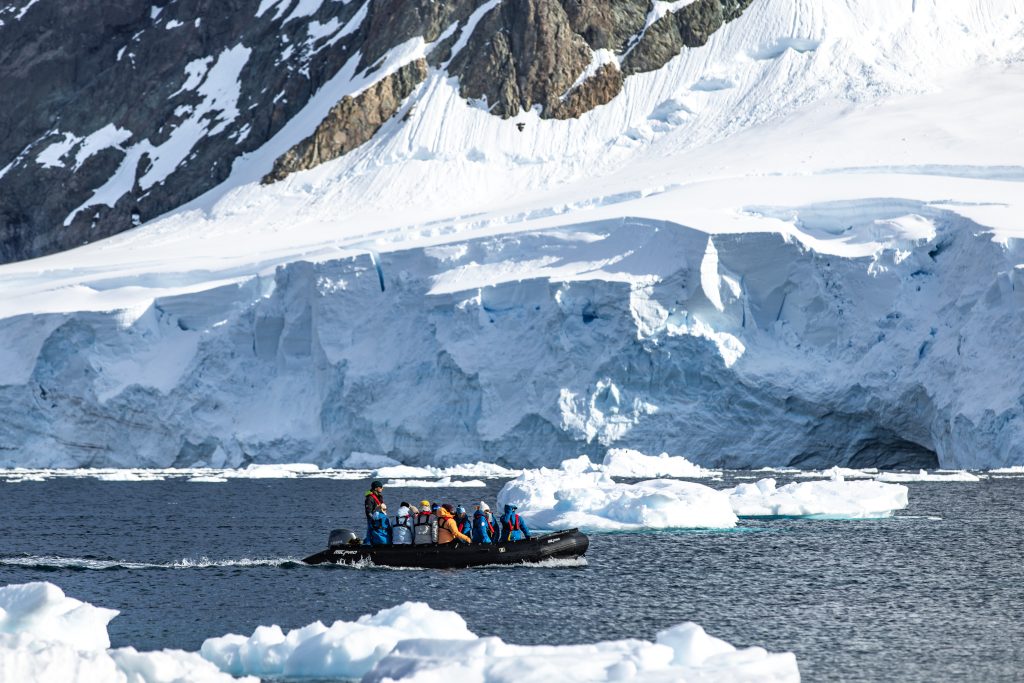 Zodiac cruising next to glacier face. 