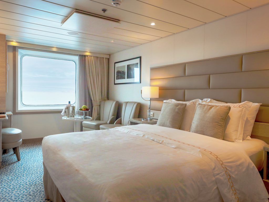 Queen bed and large window in Superior Stateroom on Exploris One.