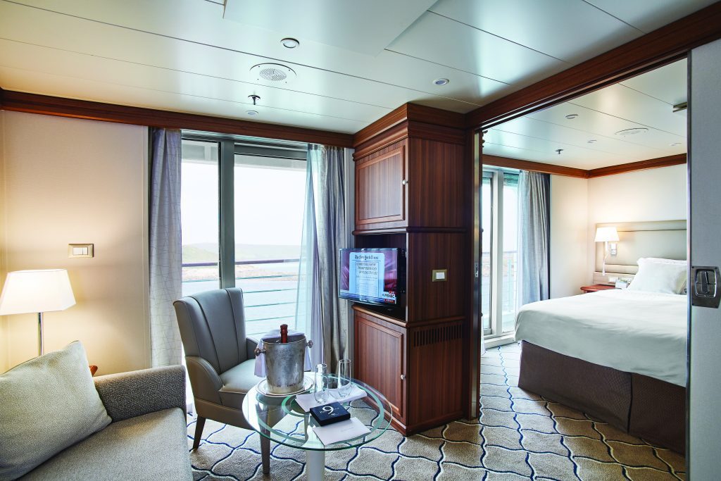 Discovery Suite on Exploris One with sitting area, bedroom with queen bed and glass sliding door leading to private balcony.