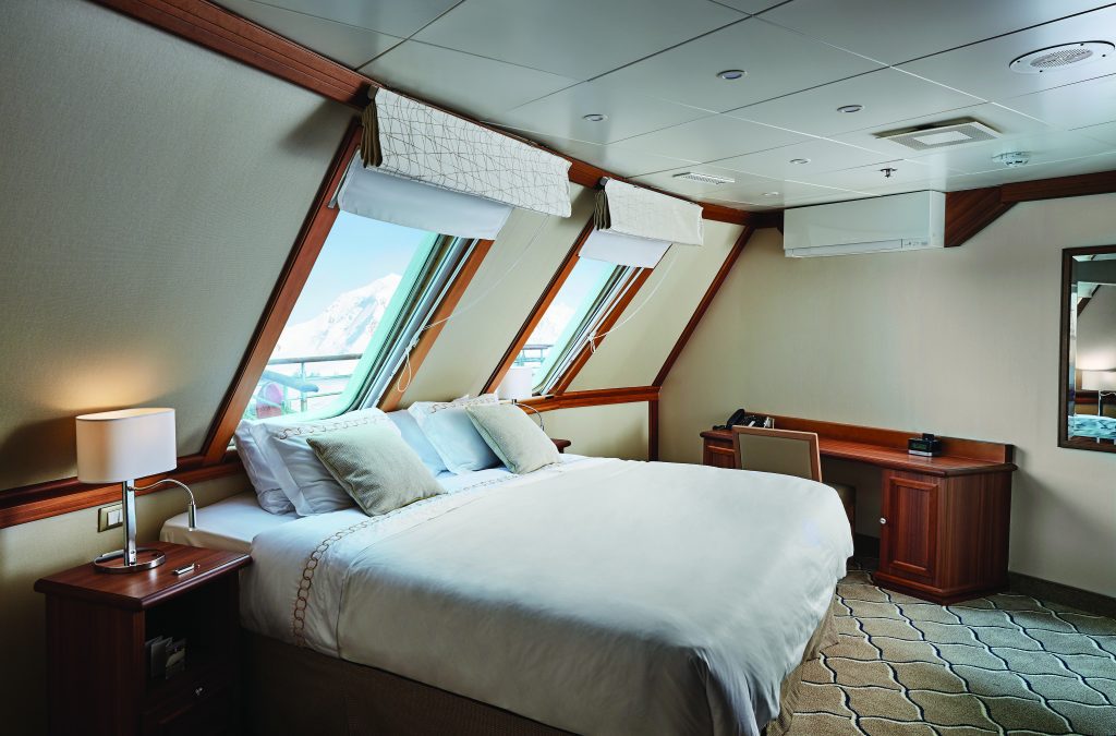 Queen bed with 2 large windows in Grand Suite on Ocean Exploris. 
