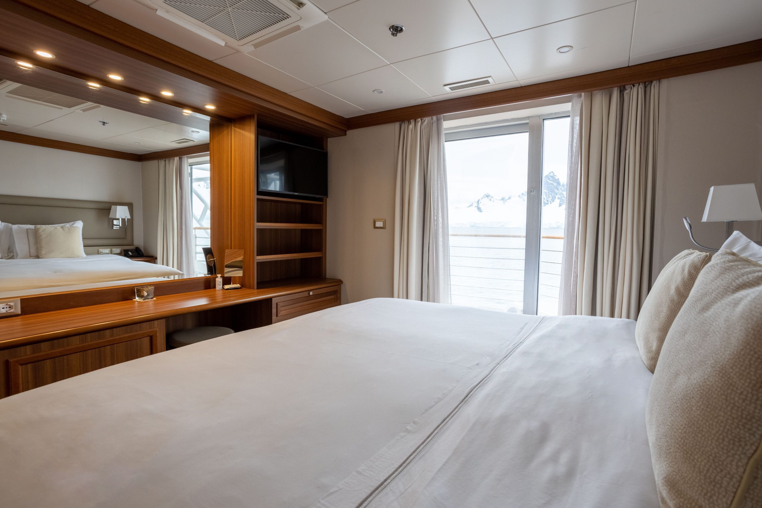 Exploris One Owner's Suite showing queen bed and large glass sliding door.