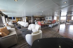 The main lounge onboard Discoverer with many chairs, coffee tables and a bar.