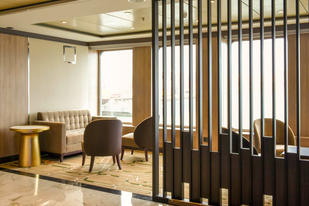 Small lounge with a couch, chairs and large windows on the ship World Voyager.