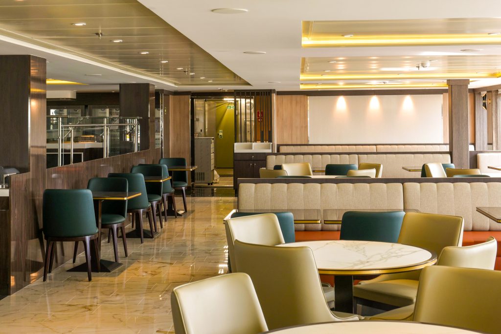 Empty restaurant on World Voyager with many tables and different colored chairs.