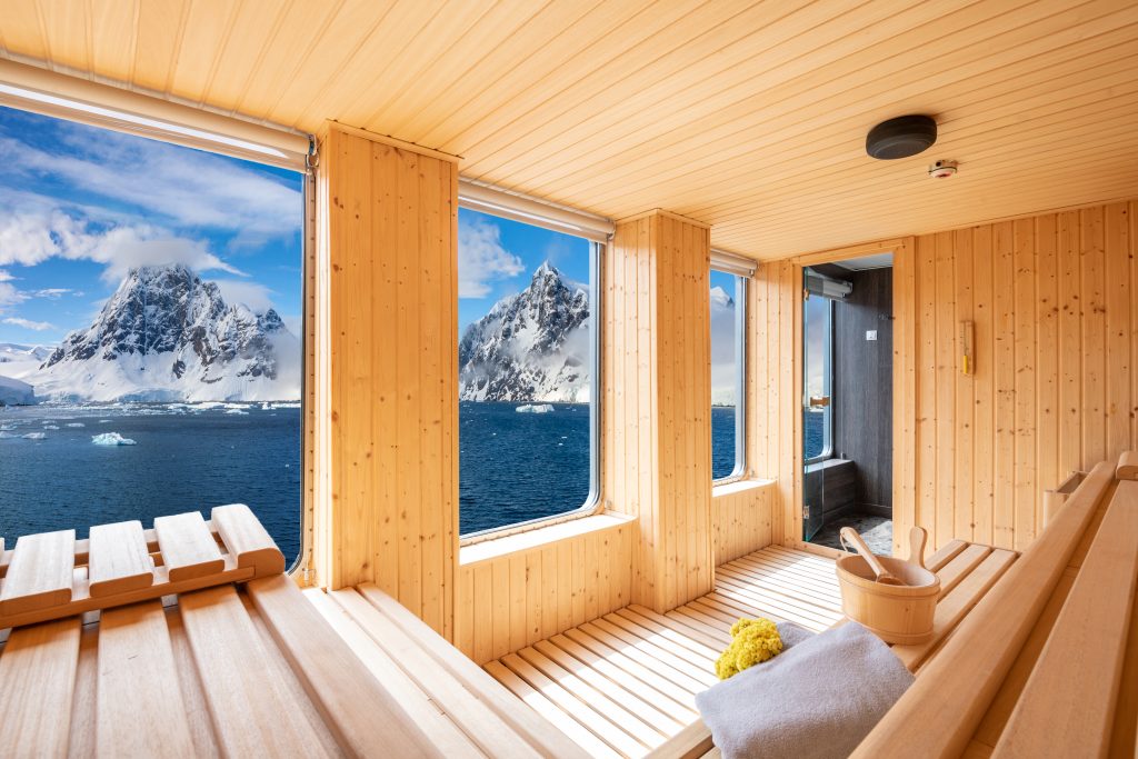 Large sauna with wooden benches and huge windows with ocean views on World Voyager.