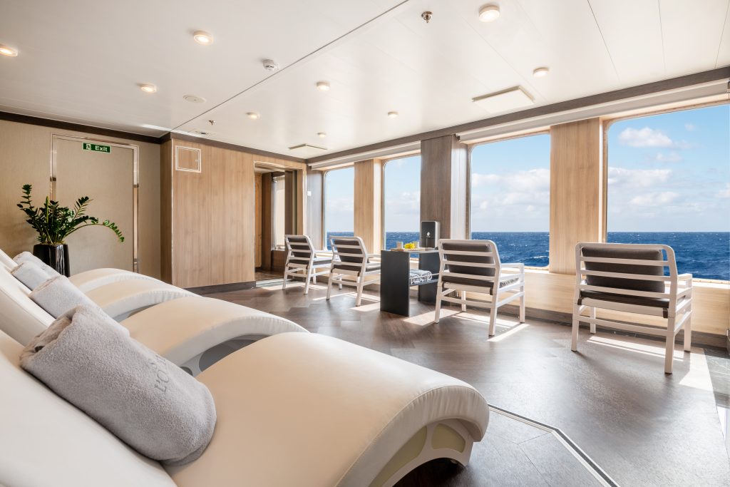 Spa room with lounge chairs looking towards windows with view of the ocean on World Voyager.