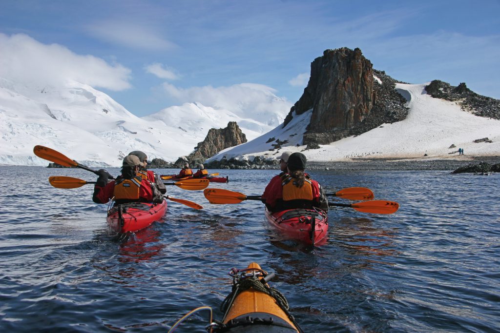 three kayaks on the water in Antarctica with guests paddling