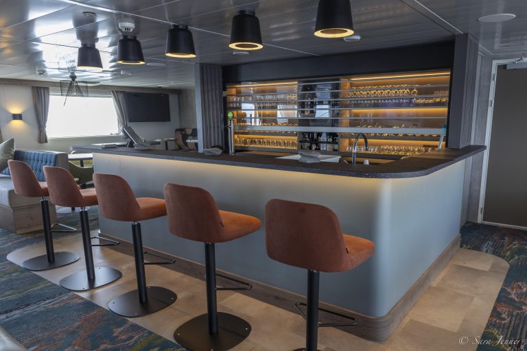 Bar with 4 fixed barstools and glasses in case behind bar on the ship Ortelius
