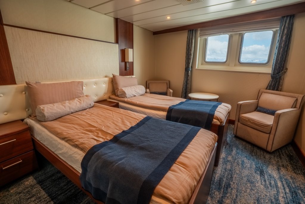 Two twin beds and two windows inside a Deluxe cabin on the Expedition ship. 