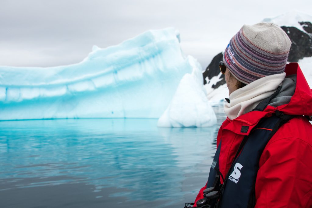 Guest sitting on zodiac looking at iceberg. 
