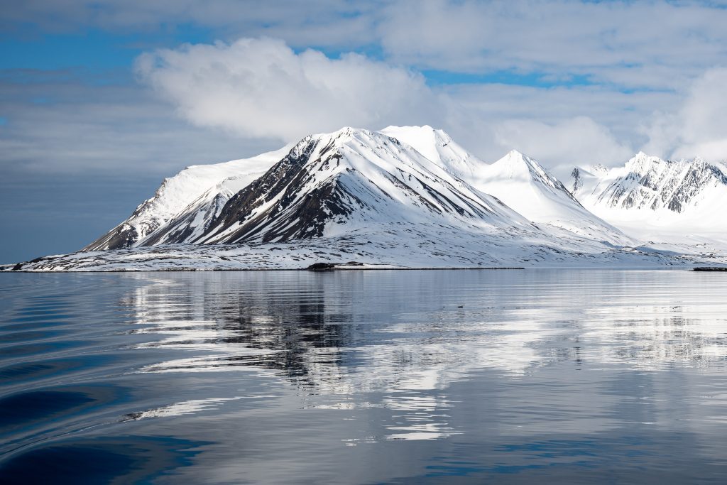 Snow covered mountains with reflection in water.