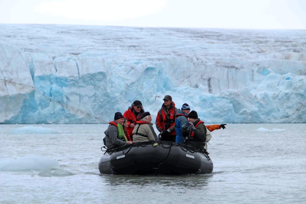Guests on a zodiac with glacier in background.