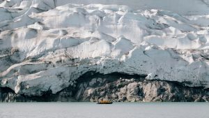A zodiac on the water in front of large glacier.