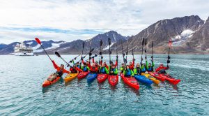 Kayakers on the water lifting paddles in the air.
