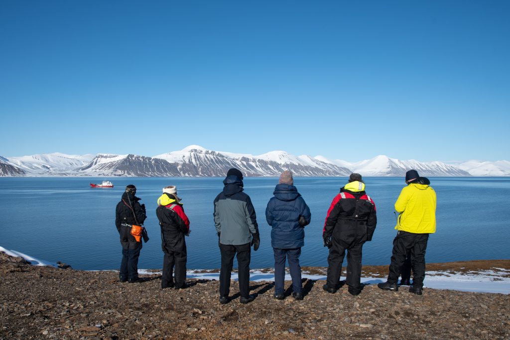 A group of guests gazing at scenic fjord in Svalbard.
