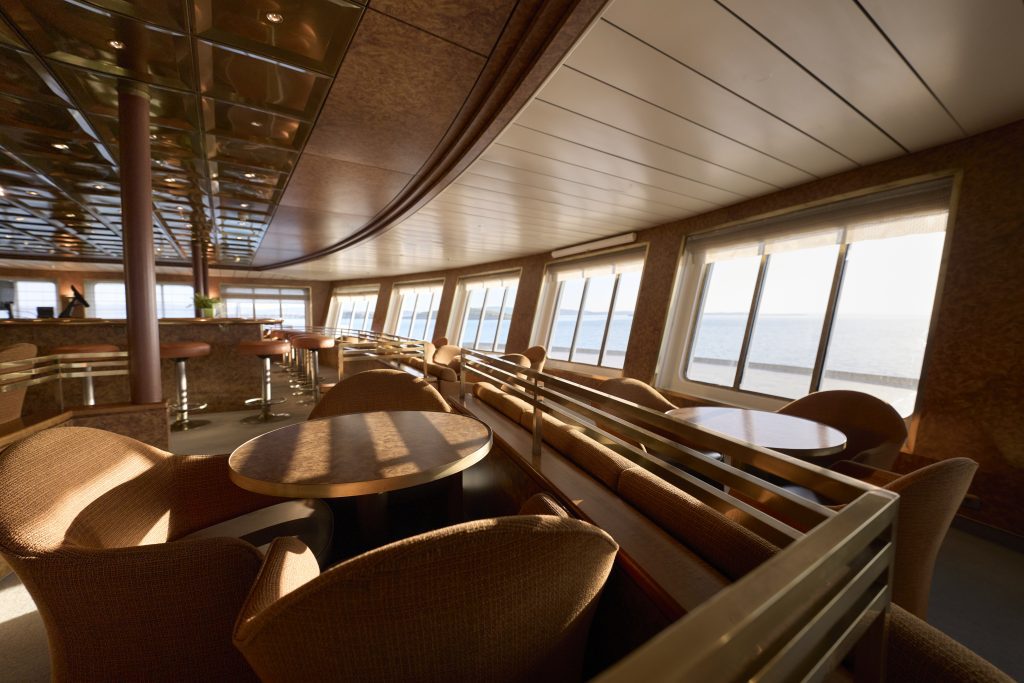 Chairs and windows looking out to the sea from the Observation Lounge on Heritage Adventurer. 