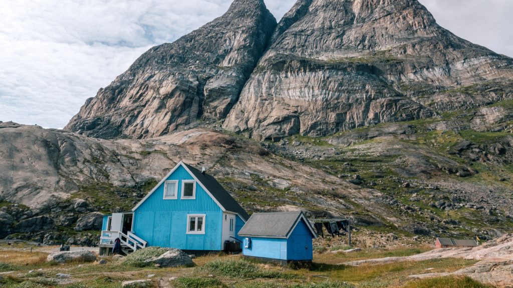 A blue house in front of dramatic mountain peak in West Greenland.