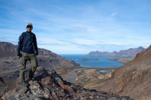 Guest standing in mountains overlooking Stromness whaling station on Shackleton hike. 