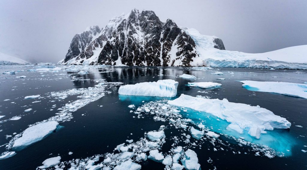 An Antarctic landscape with sea ice and steep rocky cliff. 