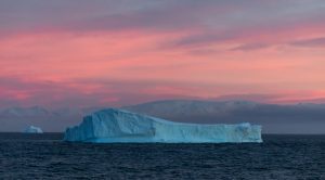 An iceberg with pink sky at sunset. 