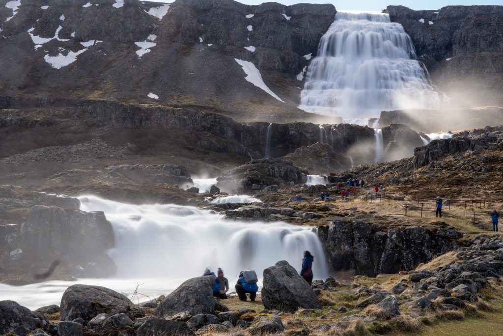 Guests standing in front of multi-tiered waterfall in Iceland. 