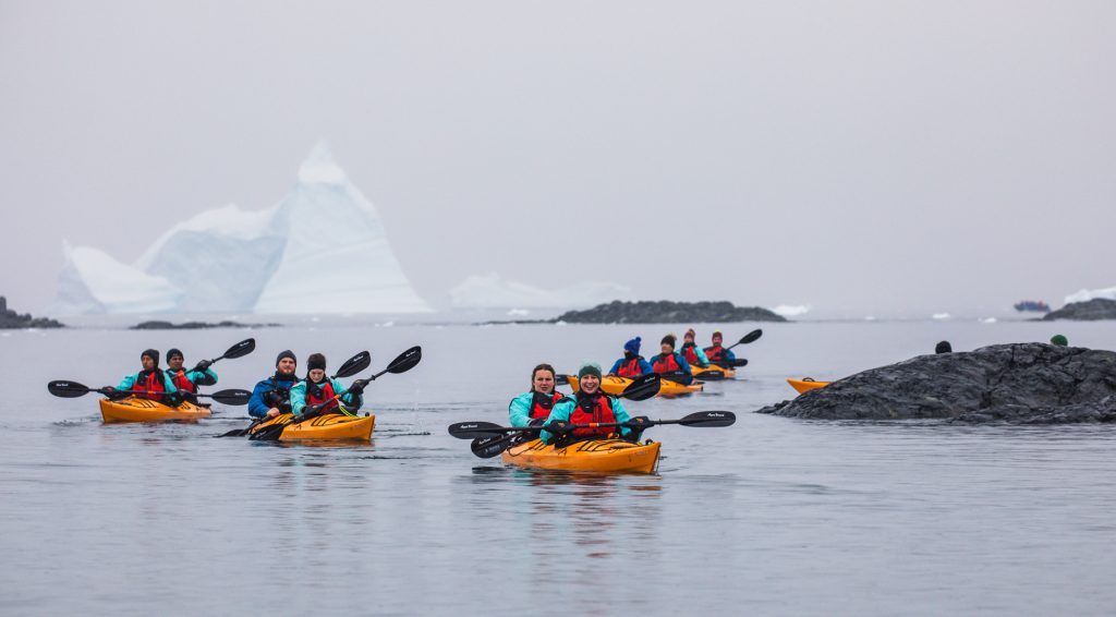 Kayakers on the water with icebergs in background. 