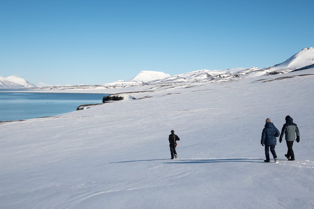 Guests hiking on the snow near shore in Svalbard. 
