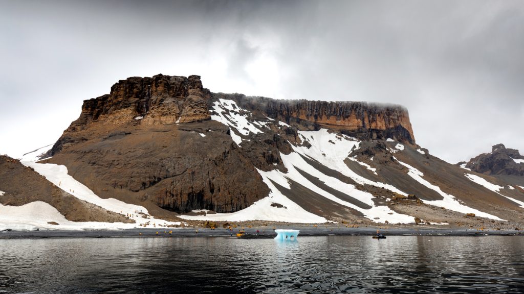Guests hiking below a brown bluff in Antarctica. 