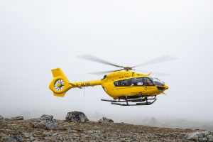 A helicopter taking off from tundra. 