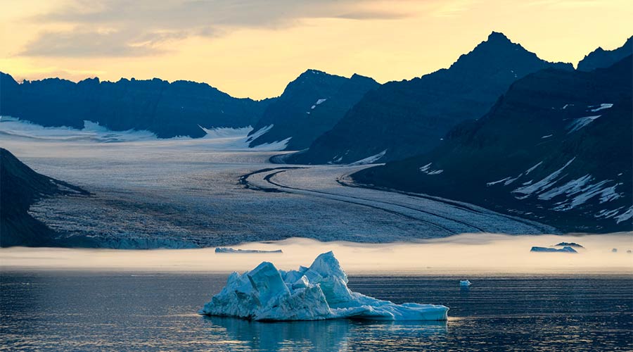A large glacier with iceberg in foreground.