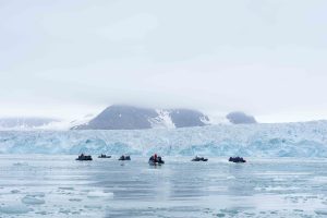 Zodiacs on the water in front of massive glacier.